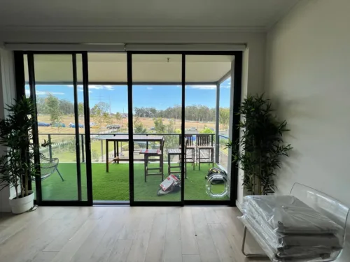 A pet door fitted in a black-framed sliding door that opens to a lawn and outdoor table