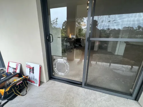 Clear pet door in a sliding glass door, with the installer's tools beside it